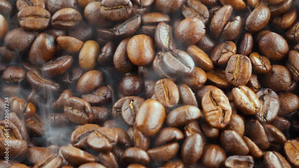 Roasted coffee beans with smoke in a frying pan. Roasted coffee beans with smoke in a frying pan.
