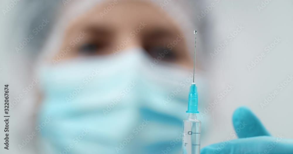 Doctor in protective uniform preparing vaccine injection, syringe closeup Doctor in protective uniform preparing vaccine injection, syringe closeup
