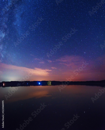 A night on the lake with a bright milky way in the sky and millions of stars glittering in the water