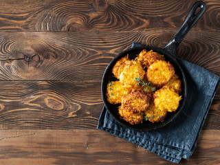 Potatoes pancakes latkes, flapjacks, hash brown or potato vada on brown wooden table. Top view or flat lay. Copy space for text.