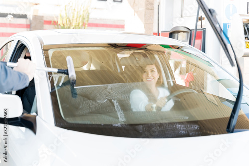 Customer Looking At Worker Cleaning Car Windshield