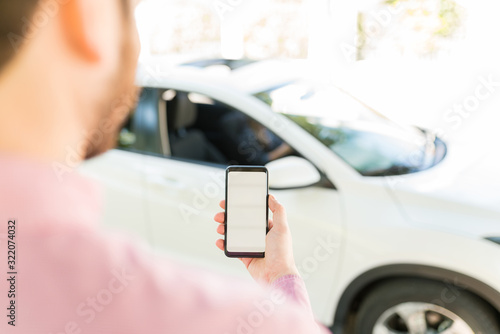 Man Holding Cellphone Against Car