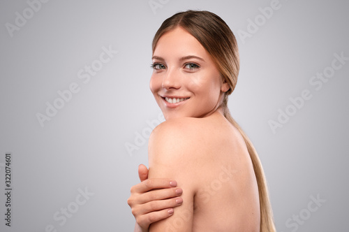 Happy young woman with clean skin embracing body