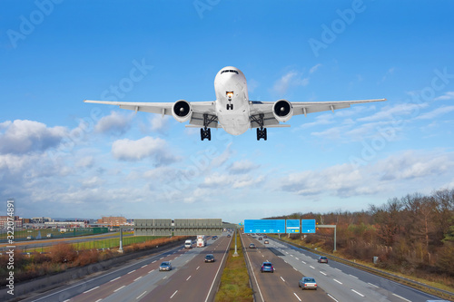 Large passenger aircraft landing over high speed highway.