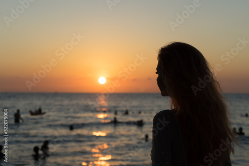 Girl on the beach looks at the sunset.