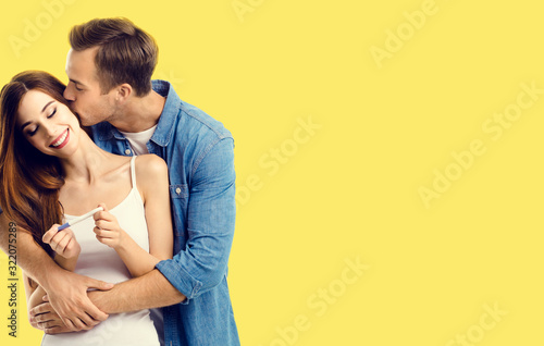 Love, relationship, happy lovers, family concept - amorous happy couple, finding out results of a pregnancy test. Yellow color background. © vgstudio