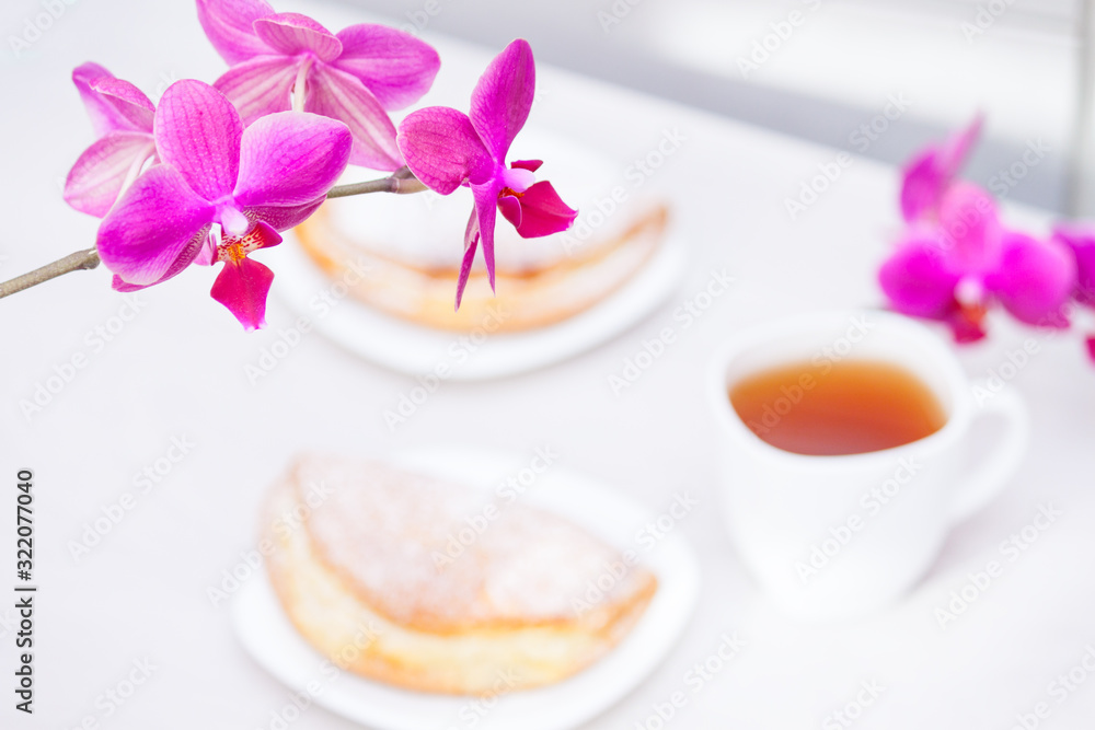Cup of tee, flowers, homemade buns with cottage cheese on white wooden background. Happy day, good morning concept.