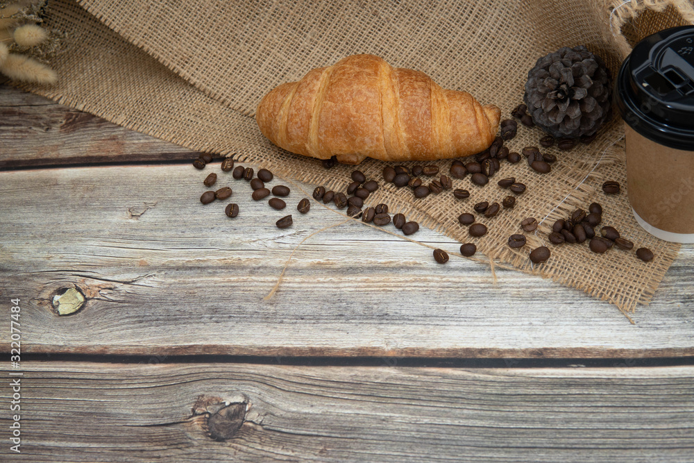 take away coffee cup , roast coffee bean and croissant on sack cloth in wooden background, homemade cafe concept take away coffee cup , roast coffee bean and croissant on sack cloth in wooden background, homemade cafe concept