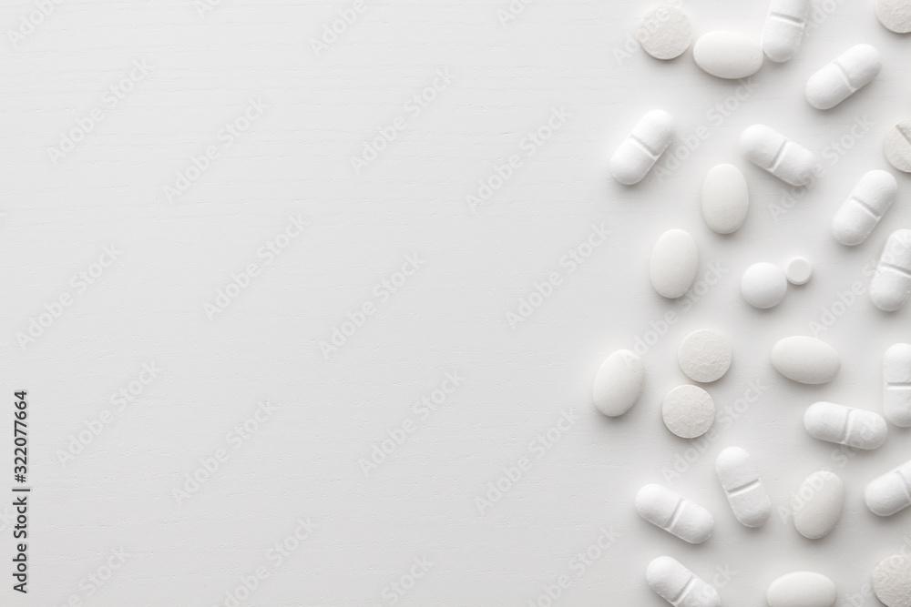Scattered white pills on a white background. Bright monochrome composition. Pharmacology. Copy space Scattered white pills on a white background. Bright monochrome composition. Pharmacology. Copy space