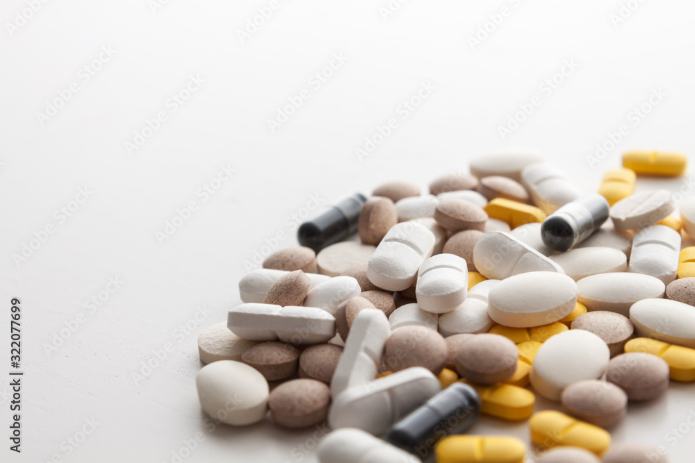 Scattered colorful pills on a white background. Copy space. Pharmacology.