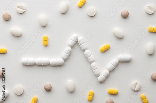 Scattered colorful pills on a white background. Pharmacology. Heartbeat, cardiogram.