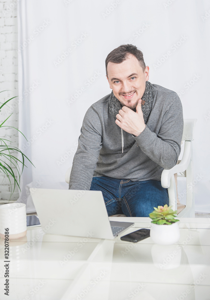 Fototapeta premium Handsome happy man working using laptop with smartphone at home