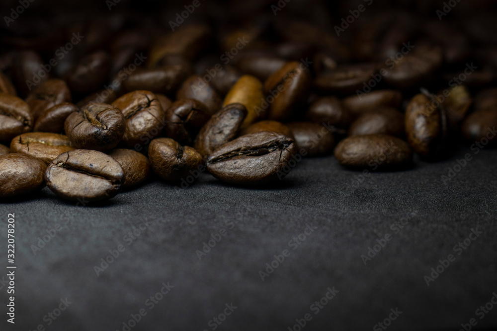 Naklejka premium Coffee in beans on dark background. Abstract background texture.Coffee beans texture. Food background of coffee beans