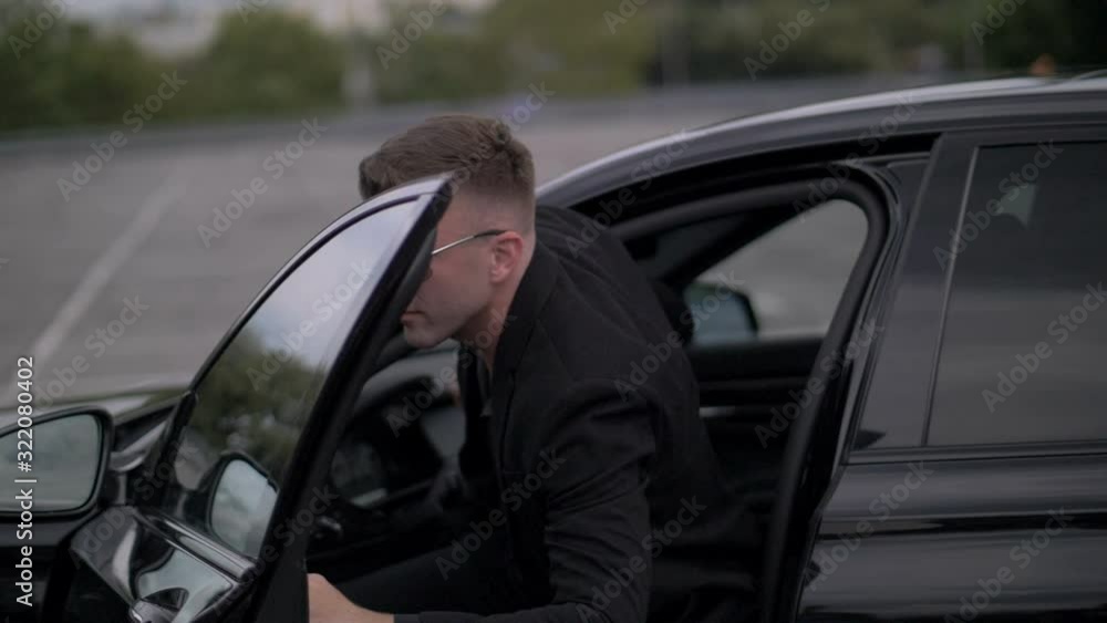 Young attractive man in black suit, getting out of the black car Young attractive man in black suit, getting out of the black car