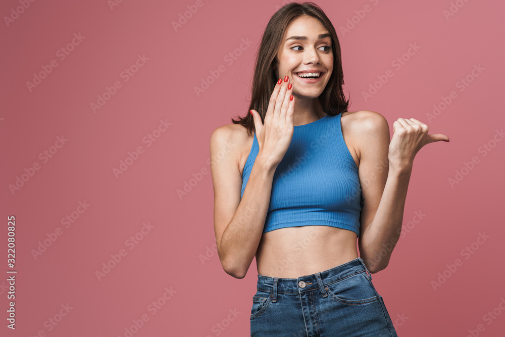 Image of young brunette woman smiling and pointing finger aside Image of young brunette woman smiling and pointing finger aside