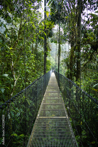 Wide angle shot of the beginning of a hanging bridge in Costa Rica  overlooking the pluvial rainforest. Impressive view of the nature around and below.