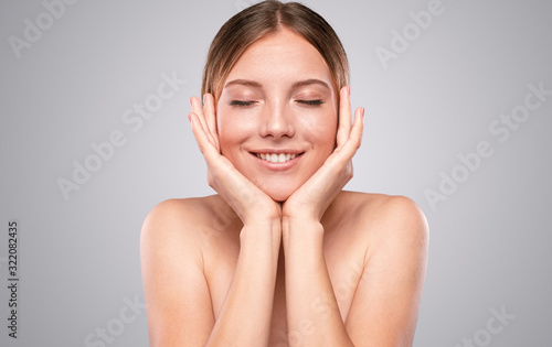 Happy model touching soft skin with closed eyes