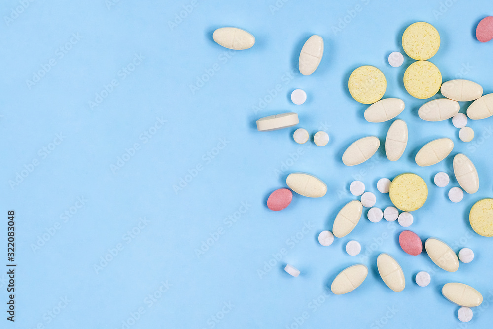 Assorted pharmaceutical medicine pills, tablets on blue background with copy space. Health care. Top view.