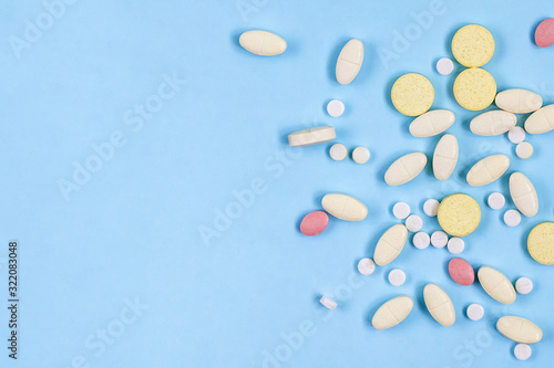 Assorted pharmaceutical medicine pills  tablets on blue background with copy space. Health care. Top view.