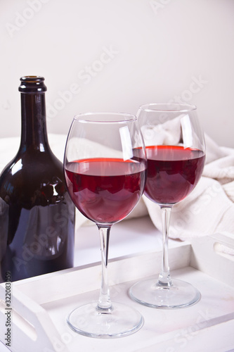 Two glasses with red grape wine with bottle on the background. Romantic dinner concept.