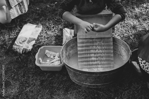 A child is washing clothes in an old zinc wash tub with wooden washboard  photo