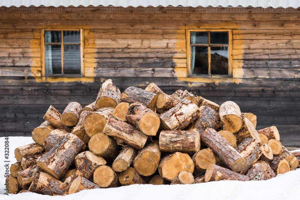 Mountain of chopped firewood on background of wooden house for harvesting for winter. Mountain of chopped firewood on background of wooden house for harvesting for winter.
