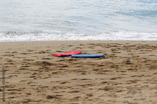 Two colorful boogie bodyboards lie on beach. Ready to ride and have fun in the ocean. Vacation time.