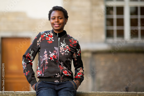 Front portrait of cool young african woman with hands in pocket