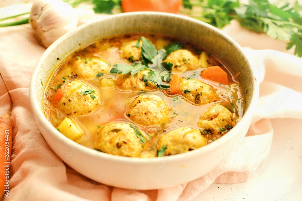 Soup with meatballs and vegetables. Vegetable soup with chicken and beans. Side view, close-up.