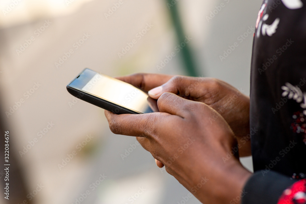 Close upafrican woman hands holding mobile phone outdoors