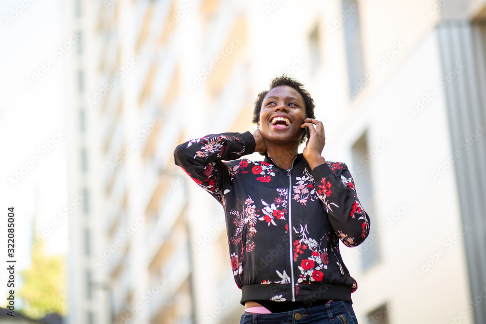 happy young black woman walking in city talking with mobile phone