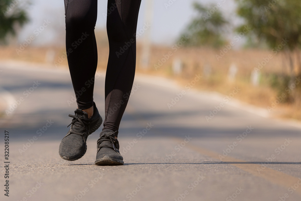 Close up Athlete running woman wearing Exercise pants and running shoe on the road,Runner woman traning in the morning.Walking for warm up her muscle. Close up Athlete running woman wearing Exercise pants and running shoe on the road,Runner woman traning in the morning.Walking for warm up her muscle.