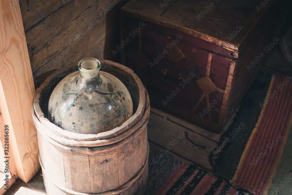 Wooden bucket with glass bottle for moonshine on the floor of the house. Wooden bucket with glass bottle for moonshine on the floor of the house.