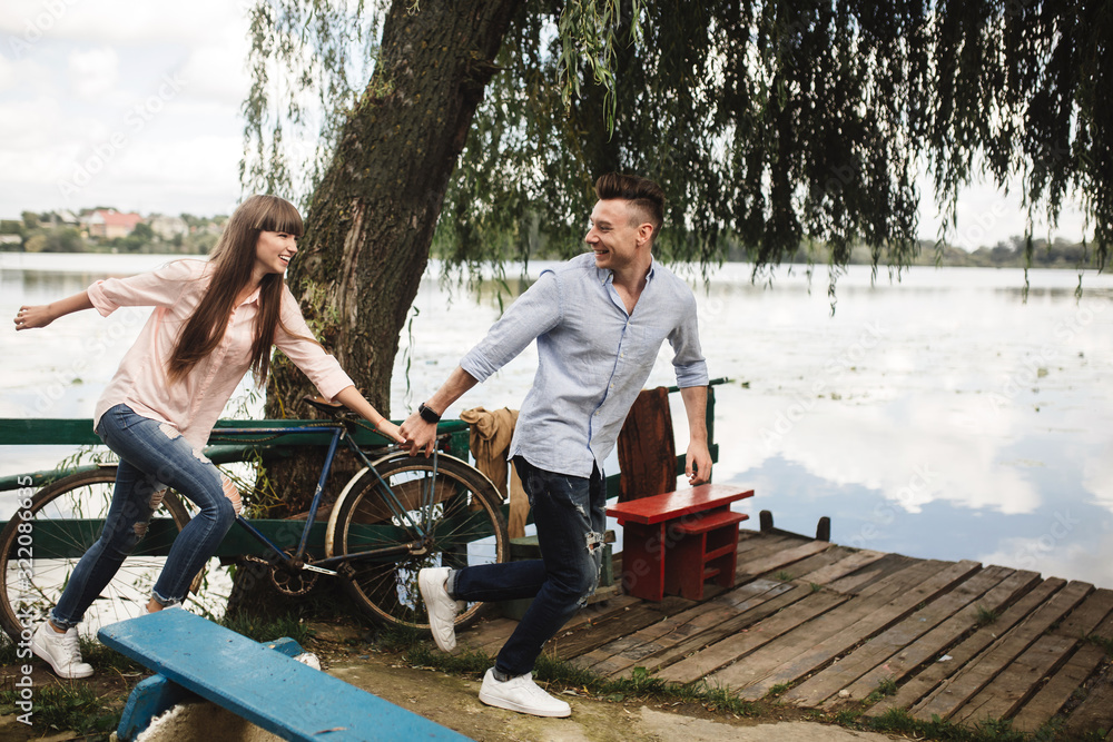 Obraz premium Happy young couple outdoors. young love couple running along a wooden bridge holding hands.