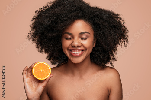 Plakat Cheerful African woman with ripe orange