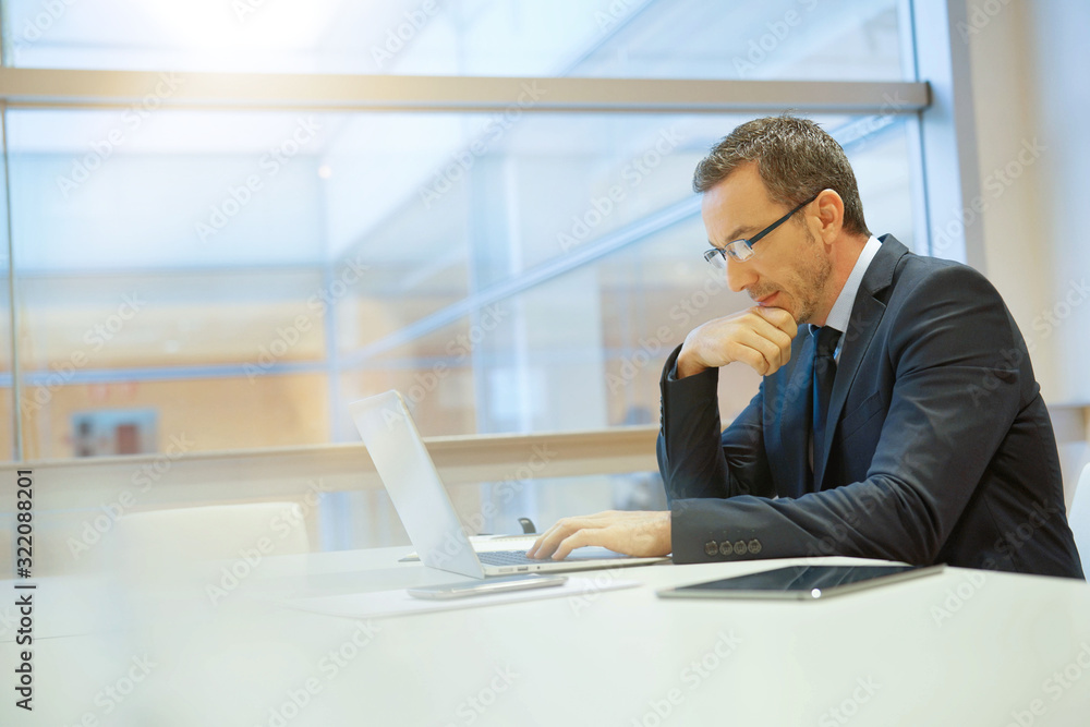 Businessman at work being thoughtful in front of laptop Businessman at work being thoughtful in front of laptop