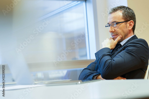 Businessman at work being thoughtful in front of laptop