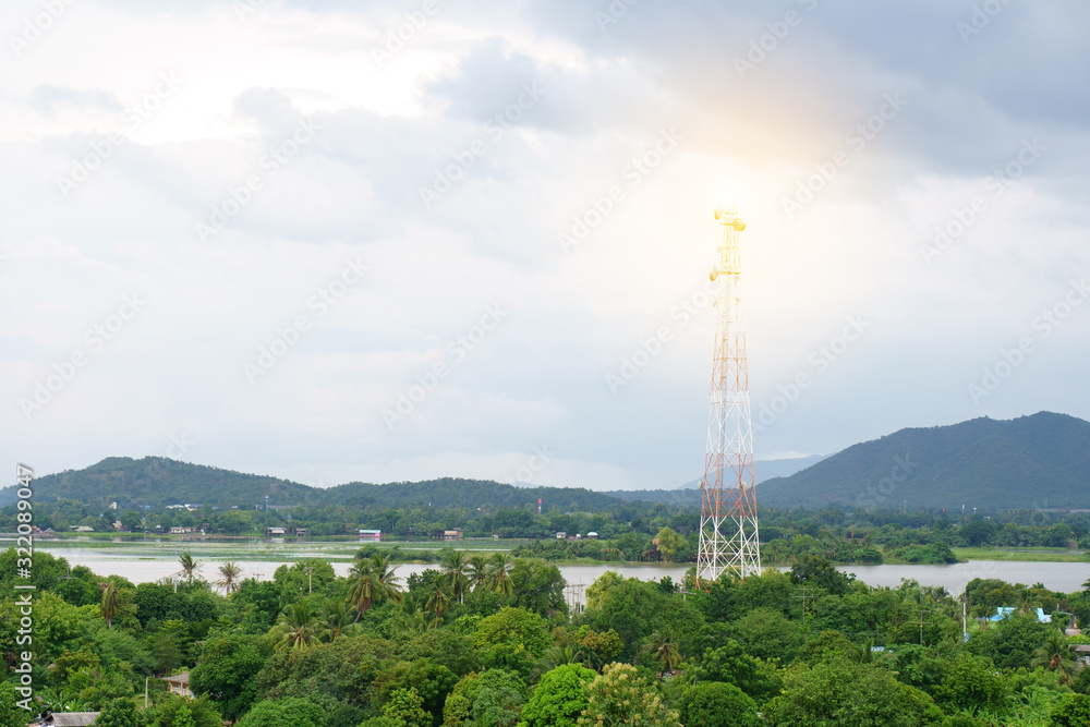 broadcasting system post and communication high tower for antenna transmission center and wireless signal technology on community with nature tree mountain and river at countryside on warm sunlight
