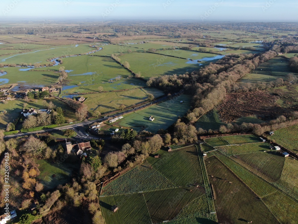 An aerial view of flat countryside with a small church in the foreground, with some flooded fields, Dorset England