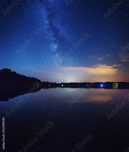 A night on the lake with a bright milky way in the sky and millions of stars shining in the water and the boat
