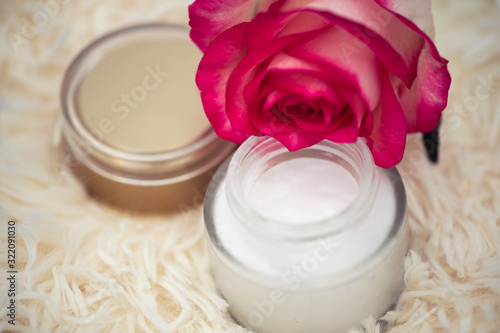 Skincare concept. cream in a glass jar with an open lid and a rose