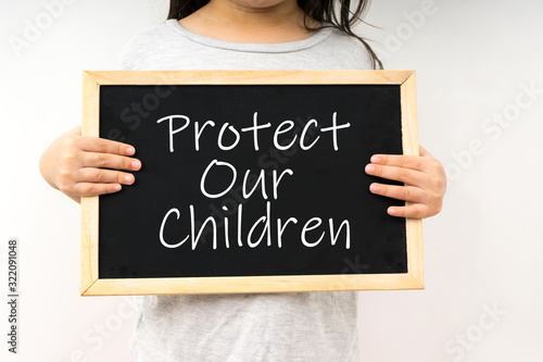 Young girl hold a chalkboard with text protect our children.