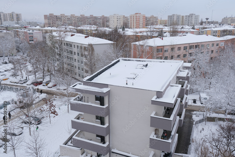 Bucharest, Romania - February 6, 2020: Winter scene in a residential area with new and old apartment block buildings, with snow covered roofs, in Bucharest, Romania, after a mild snow.