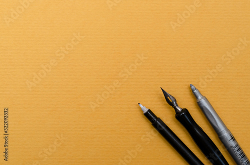 Calligraphy pen and markers on blank yellow textured paper. Place for text. 