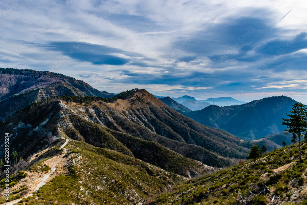 Beautiful captivating landscape of the layered French Alps mountain range in Alpes-Maritimes in the afternoon during a sunny day with a hiking path trail