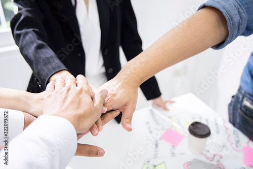 Colleagues are gathering hands to encourage each other to work. For successfully complete project. Employees are working in modern office. (Agile and Scrum in retrospective and sprint review process). photo