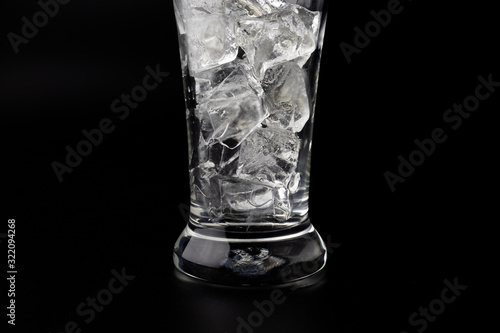 Glass with ice cubes on black background