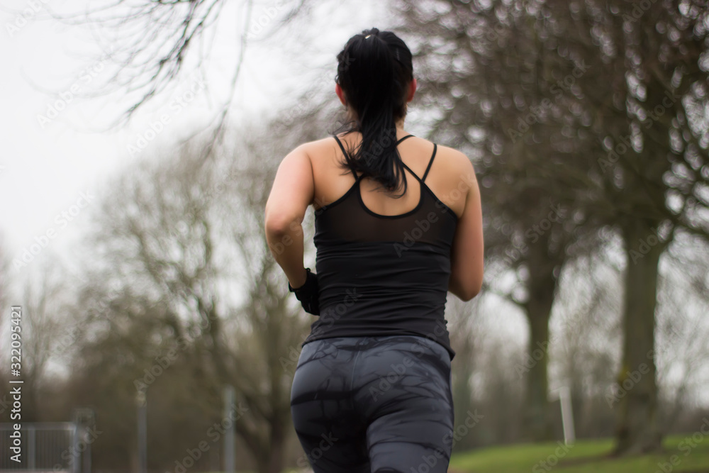 Sporty woman running in park. Back view Sporty woman running in park. Back view