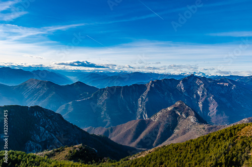 Beautiful captivating landscape of the layered misty hazy French Alps mountain range in Alpes-Maritimes in the afternoon during a sunny day © k.dei