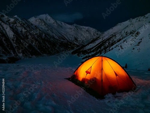 Overnight in the winter mountains. A tourist looks into the night starry sky. Red tent in the highlands © Alex Sipeta